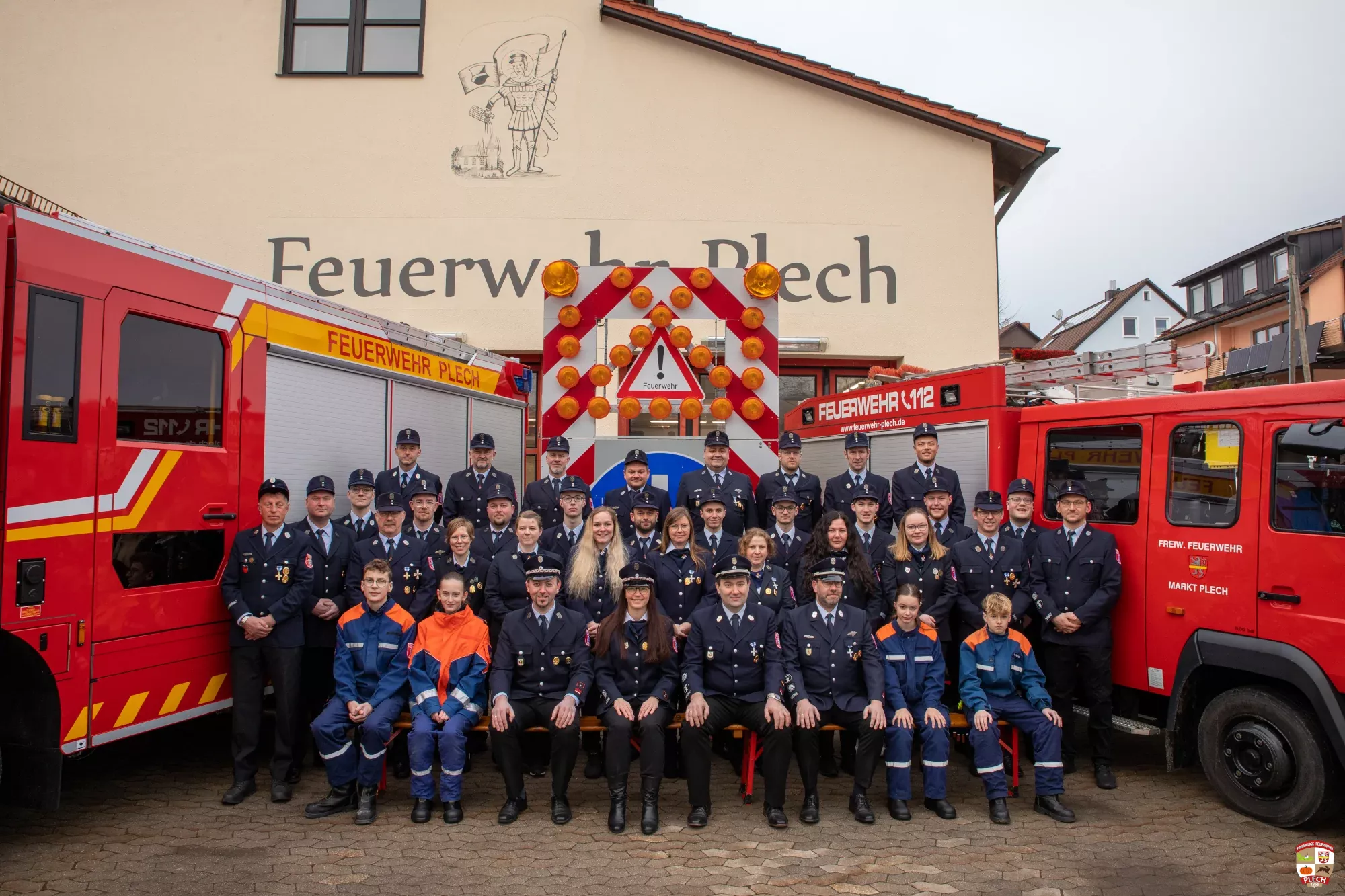 Mannschaftsfoto der Feuerwehr im Dienstanzug, flankiert von den beiden Fahrzeugen HLF 20 und LF 8/6